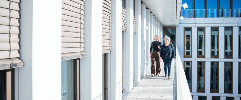 Menschen laufen auf einem Balkon neben Dachterrasse